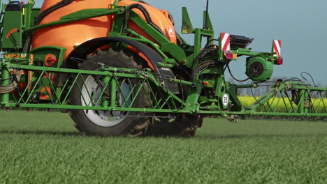 farming tractor driving by the camera and applying pesticides with sprayer