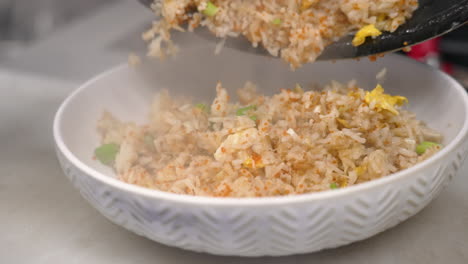 el chef arroja arroz frito de cangrejo recién preparado en el plato, cámara lenta de primer plano 4k