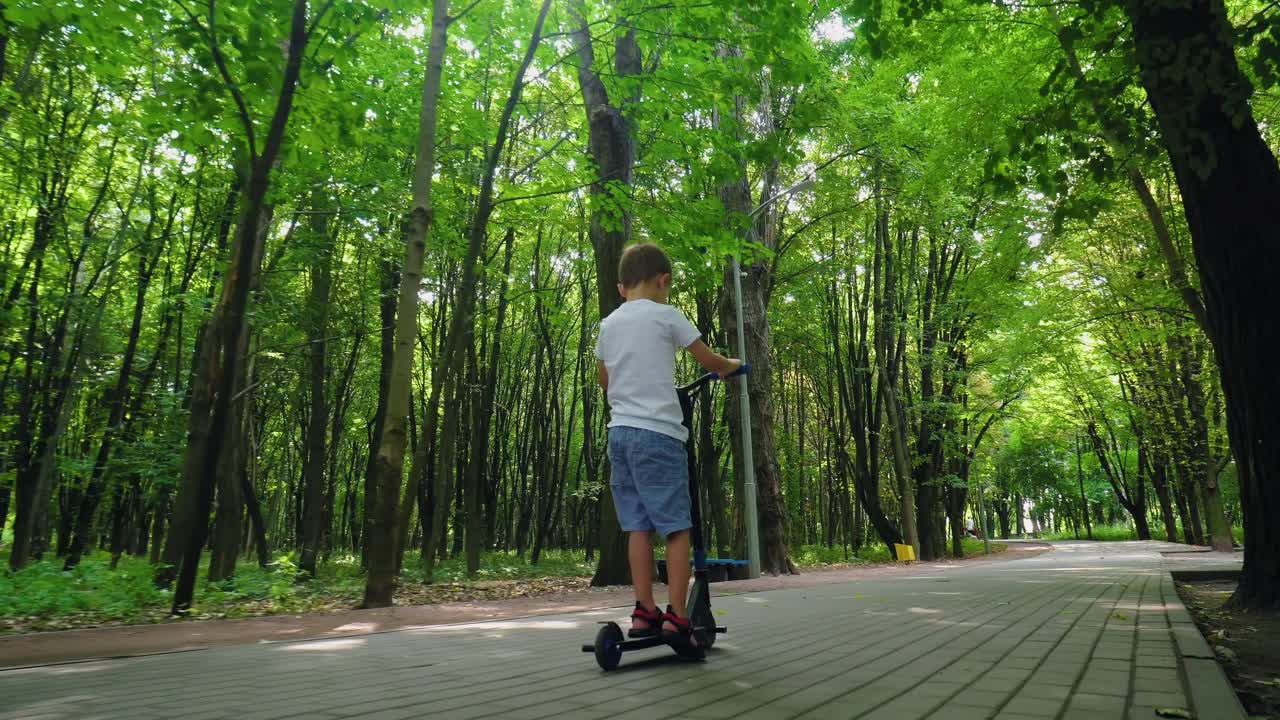 A boy rides a scooter in a city park 05
