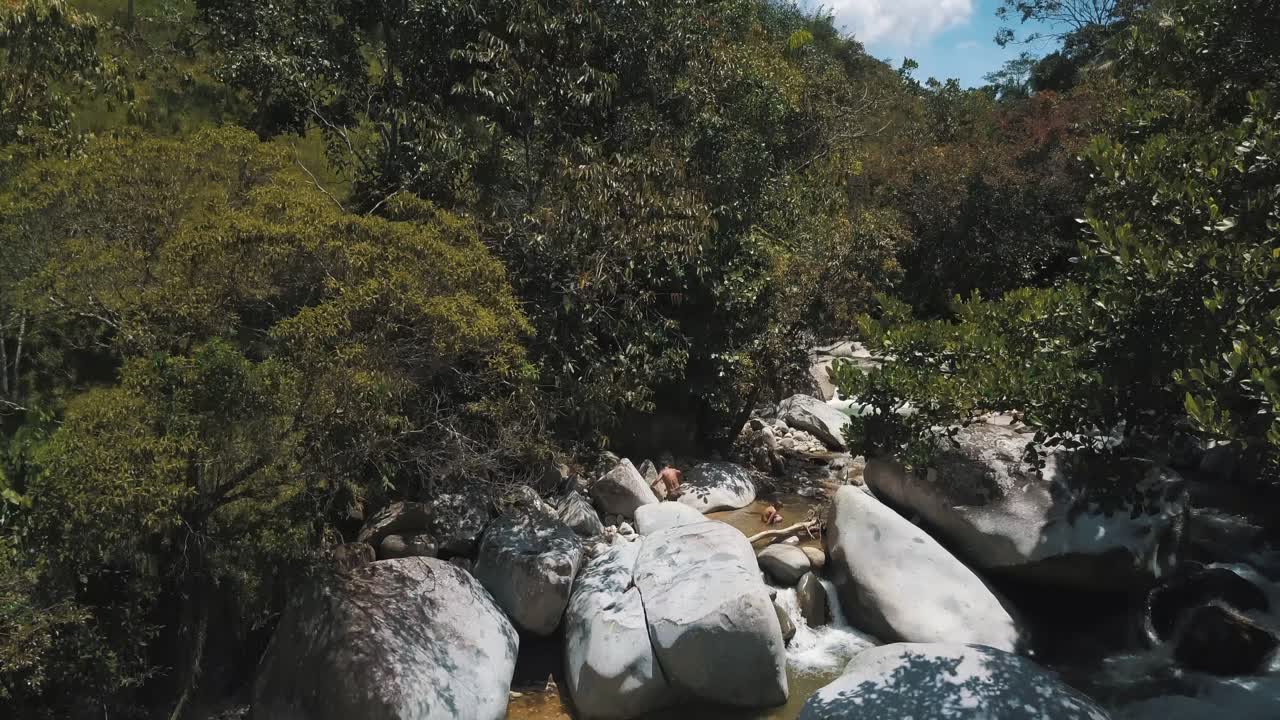 toma aérea de un dron de un río en el bosque con una cascada y enormes rocas en colombia