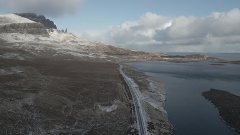 Verschneite-Berglandschaft-In-Der-Nähe-Der-Skye-Bridge-In-Schottland,-Mit-Freier-Sicht-Auf-Die-Serpentinenstraße-Und-Die-Umliegenden-Gewässer,-Aufgenommen-Bei-Tageslicht,-Luftaufnahme