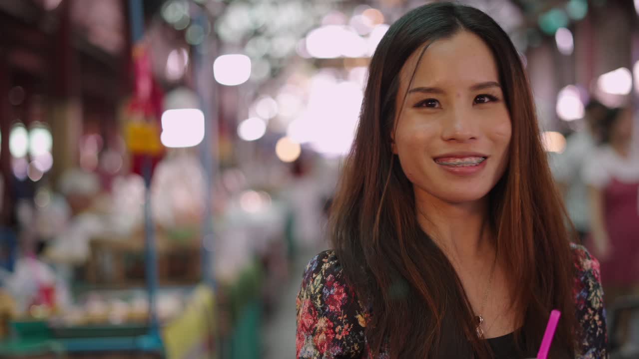 Young Asian Woman Enjoying a Drink at a Vibrant Night Market