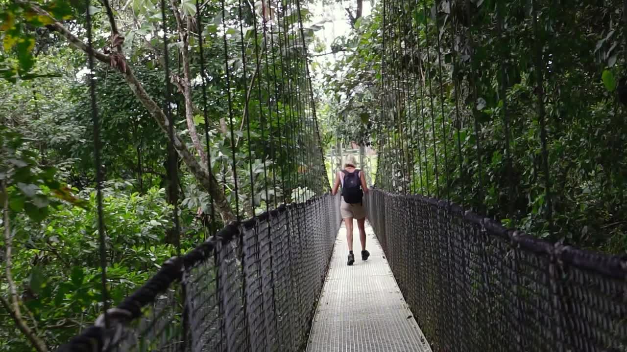 una niña cruza un puente colgante en el bosque nuboso de costa rica, monte verde