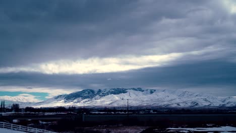 storm blowing in over the snowy, winter mountains - cloudscape time lapse