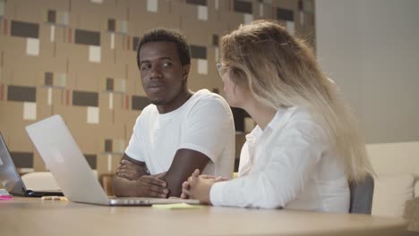 un par de profesionales sentados a la mesa con computadoras portátiles