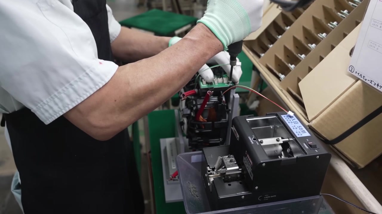 Technician using precision electric screwdriver to secure electronic components on rice cooker control board