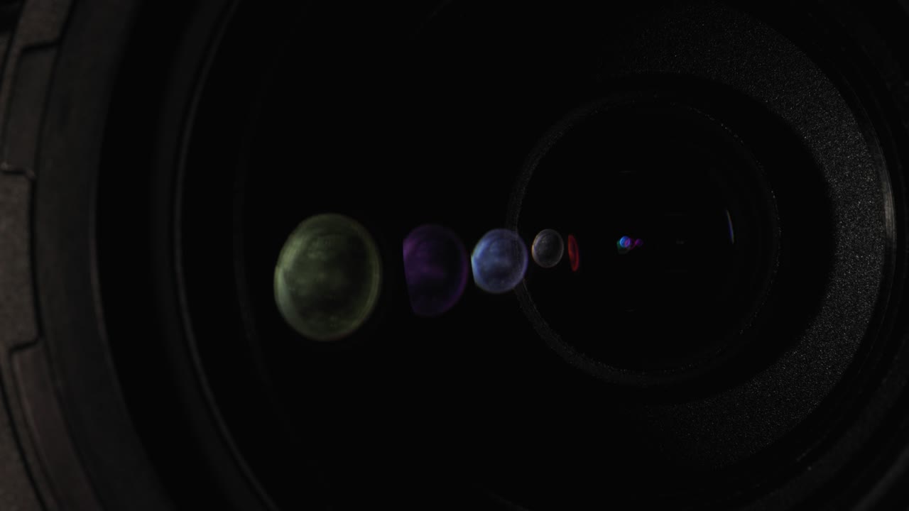 A beam of light illuminates the front lens of the camera lens