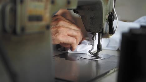 persona que utiliza una máquina de coser de época para coser tela blanca