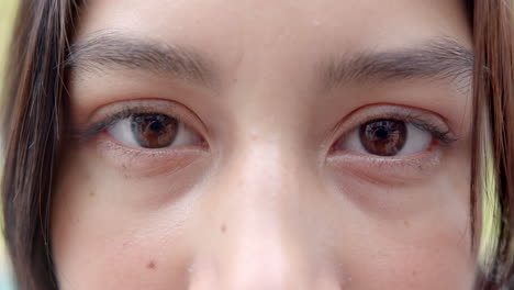 Portrait-close-up-of-brown-eyes-of-happy-biracial-teenage-girl-smiling-outdoors,-slow-motion