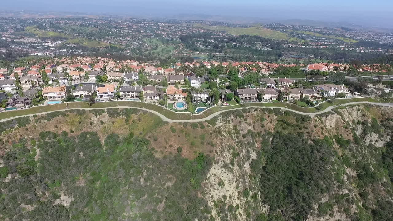 Rotating aerial drone shot flying over luxury homes in Laguna Niguel, Orange County, California that face Aliso Creek