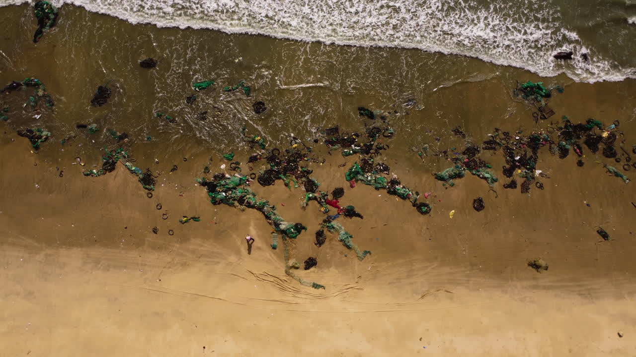 Vietnam tropical beach filled with plastic fishing net washed out after typhoon during monsoon season, consequence of climate change disasters and displacement, aerial ocean view