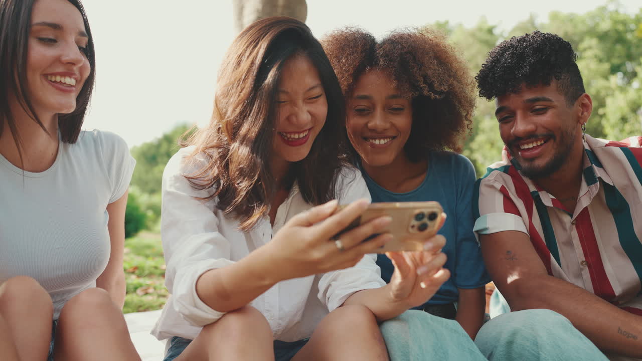 A group of friends watching a mobile phone in a park
