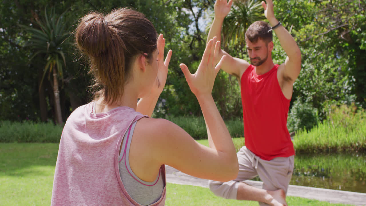 instructora de yoga caucásica practicando yoga con un hombre caucásico en el parque