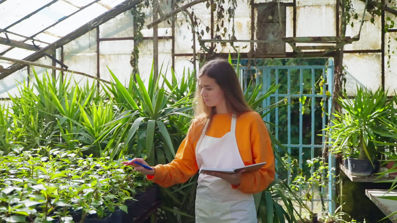 mujer jardinera tomando notas en un invernadero