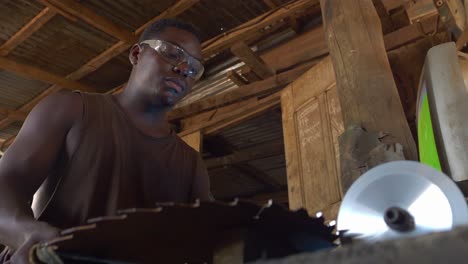 low angle close up of black male labor working class at work in a metallurgic factory wearing protective glasses focus on his job