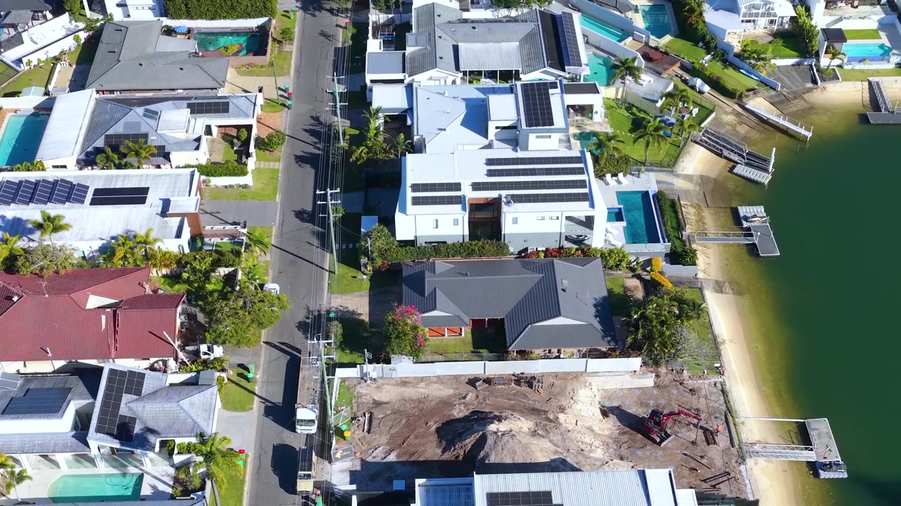 High-angle drone shot of upscale canal-front residences and a construction site in Broadbeach Waters, Australia.
