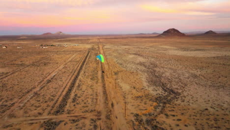 flight alongside a powered paraglider in the mojave desert during a colorful golden sunset