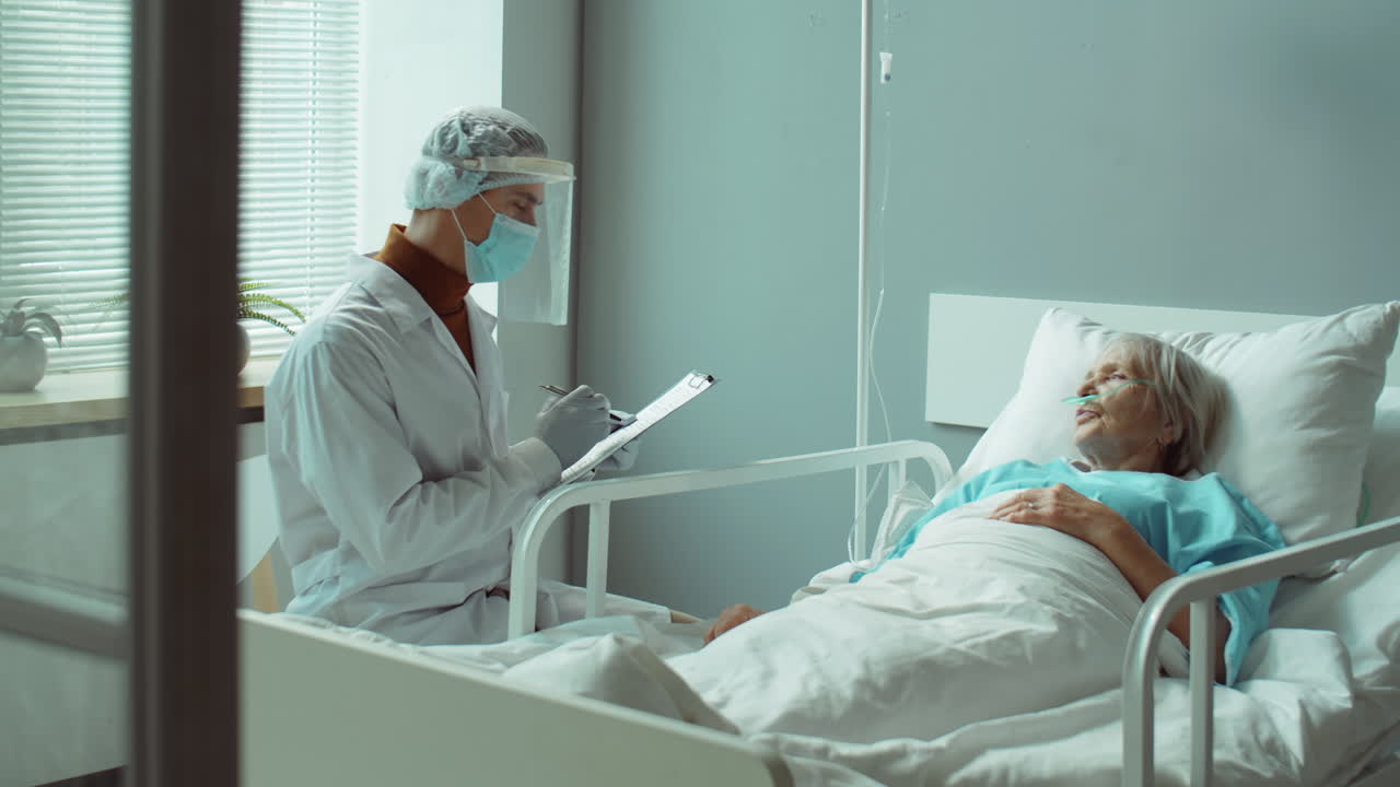 médico en uniforme de protección hablando con una mujer mayor en el hospital
