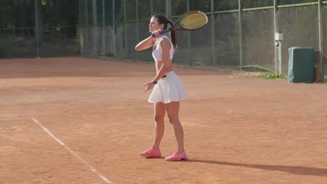 아름다운 테니스 소녀가 야외 코트에서 을 연습하고 있습니다.