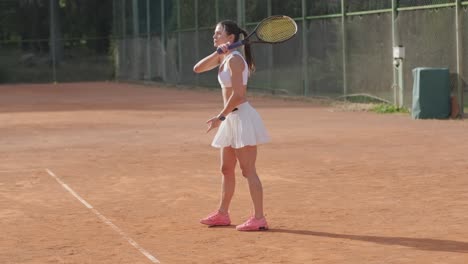 hermosa tenista practicando el servicio en la cancha al aire libre