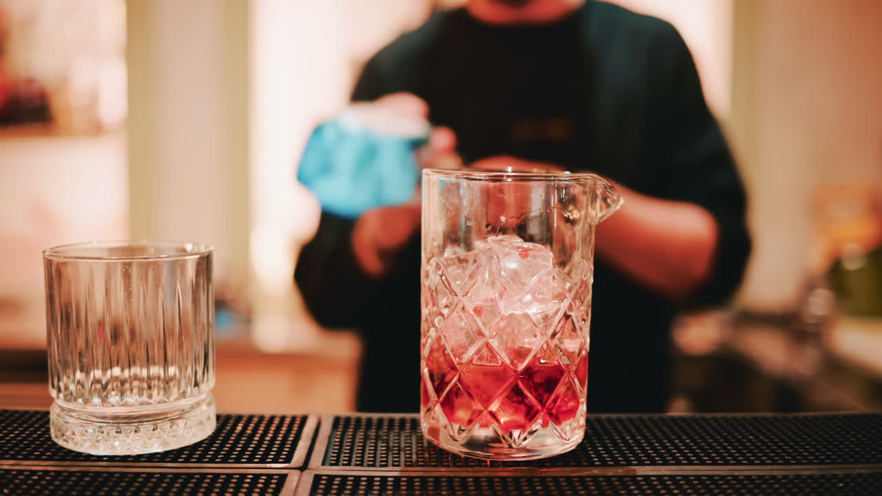 A dynamic shot of a bartender pouring a Campari shot into the mixing glass