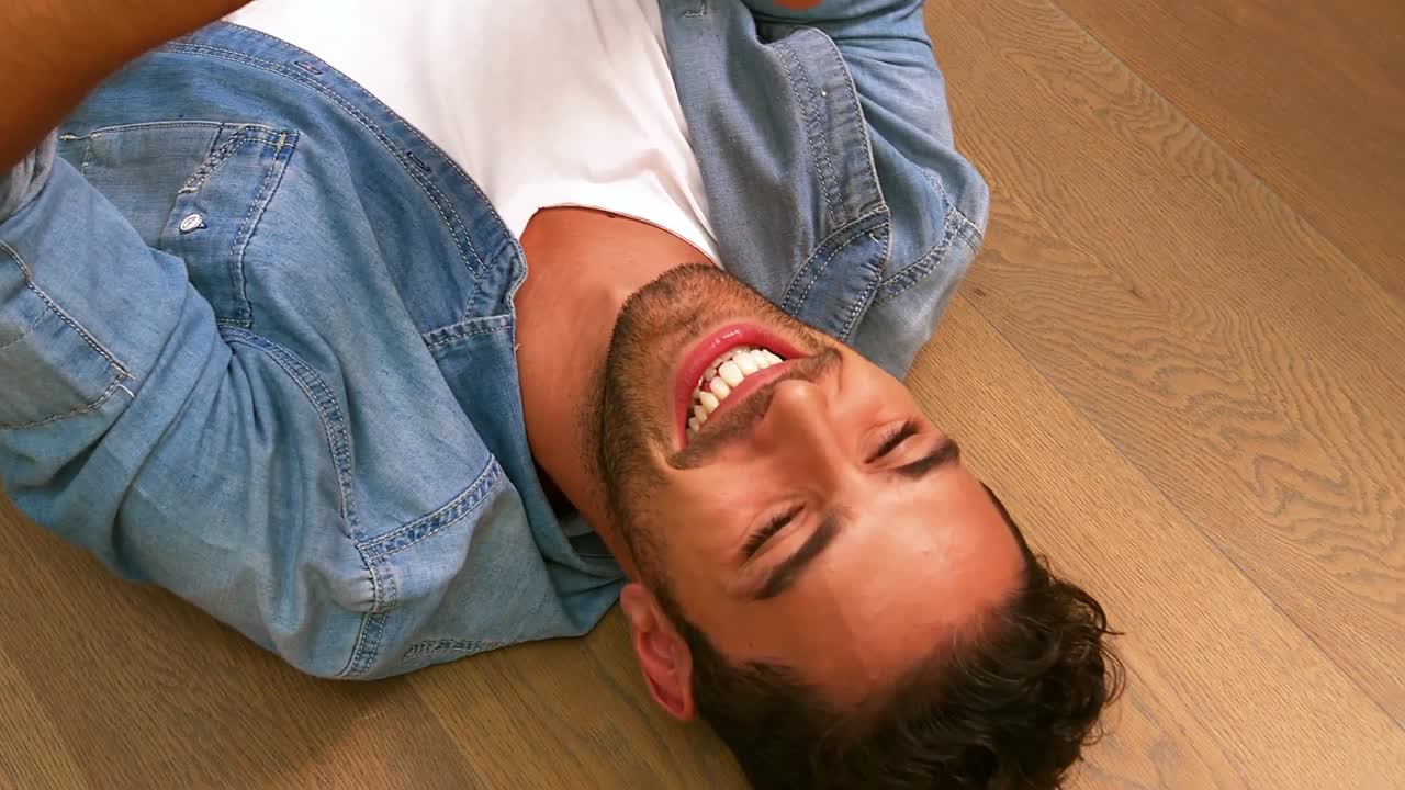 Handsome man using smartphone lying on the floor