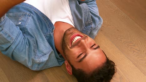 handsome man using smartphone lying on the floor