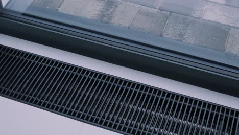 an up-close view of a modern, clean-lined hvac floor register near a window, blending seamlessly with the sleek interior design