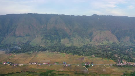 toma aérea hacia atrás de la aldea y los campos en la isla de samosir en el lago toba en el norte de sumatra, indonesia