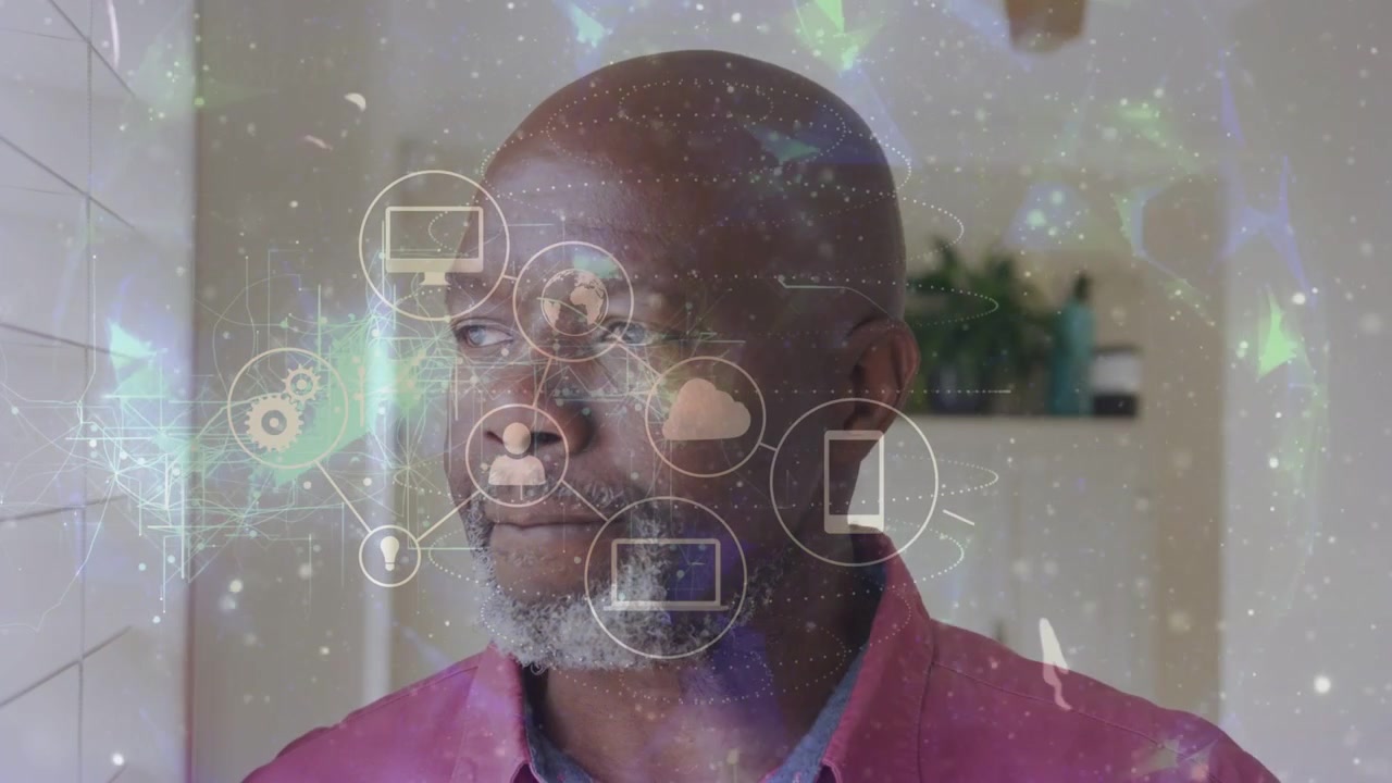Mature man standing by window, following appearing cloud and device icons visualizing tech network