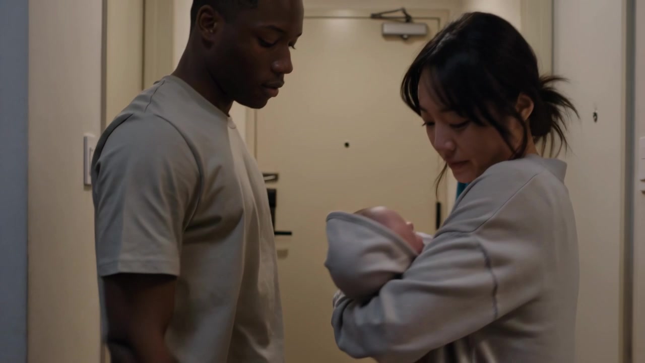 Handing couple passing swaddled baby in entryway, woman reaching in robe, for care