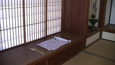 a scroll of calligraphy rests on a shoji desk in a japanese house