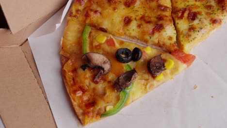 hand places mushroom on vegetarian pizza with olives, corn and paprika, close-up