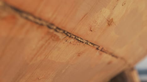 slider shot of rustic gritty old mastic sealant in between carvel constructed sapele timber planking on old sailing boat