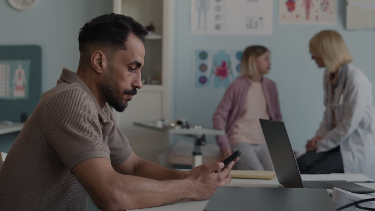 Doctor consulting with patient and father using laptop in medical office