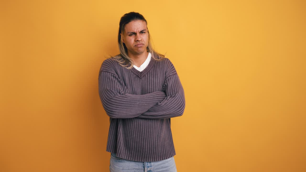 Annoyed Young Man with Arms Crossed on Yellow Background