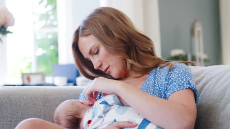 Slow-Motion-Shot-Of-Mother-Sitting-On-Sofa-At-Home-And-Breastfeeding-Baby