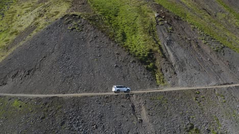 Luftaufnahme-Eines-Weißen-Lieferwagens-Auf-Einer-Gefährlichen-Straße-Am-Rande-Eines-Felsigen-Berges-In-Island