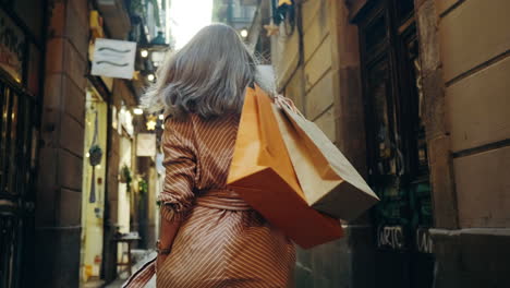 back view of woman walking with shopping bags. smiling girl flirting on camera