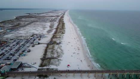 aerial view of crowded beach with pier and turquoise water