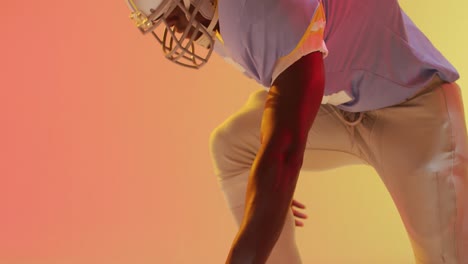 video of midsection african american american football player with ball over orange background