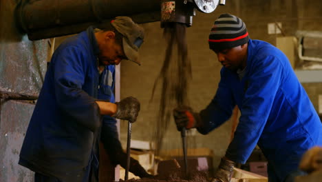 workers putting soil in metal mold in foundry workshop 4k