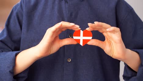 the girl holds in her hands a heart in the form of a flag of denmark.