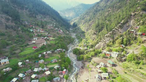 Video-Aéreo-De-Un-Hermoso-Valle-Verde-De-Cachemira-Con-Río,-Montañas-Y-Colinas,-Techos-Y-Caminos---Belleza-De-Cachemira