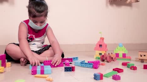 little girl wearing mask playing with colorful lego dices