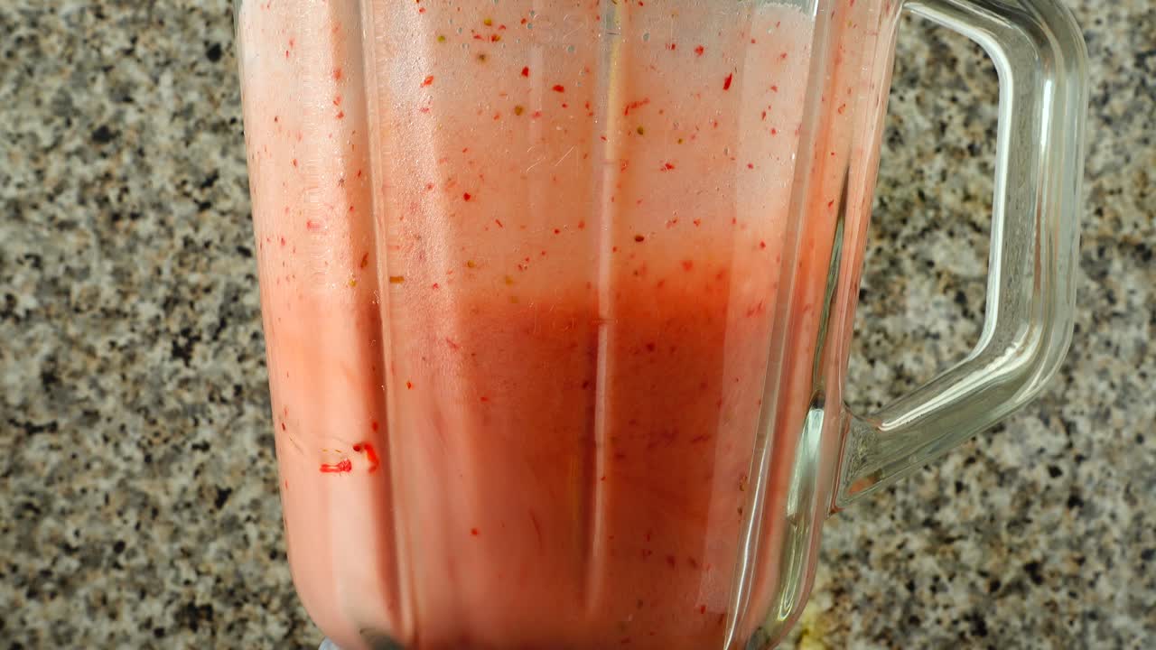 Tilberedning av cocktail i blenderen med epler, bananer og jordbær. Filming på kjøkken.