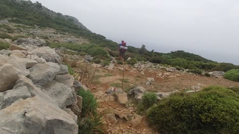 A-hiker-carrying-camping-gear-is-walking-away-on-an-open-terrain-with-a-gentle-slope-on-Lycian-Way-in-Turkey