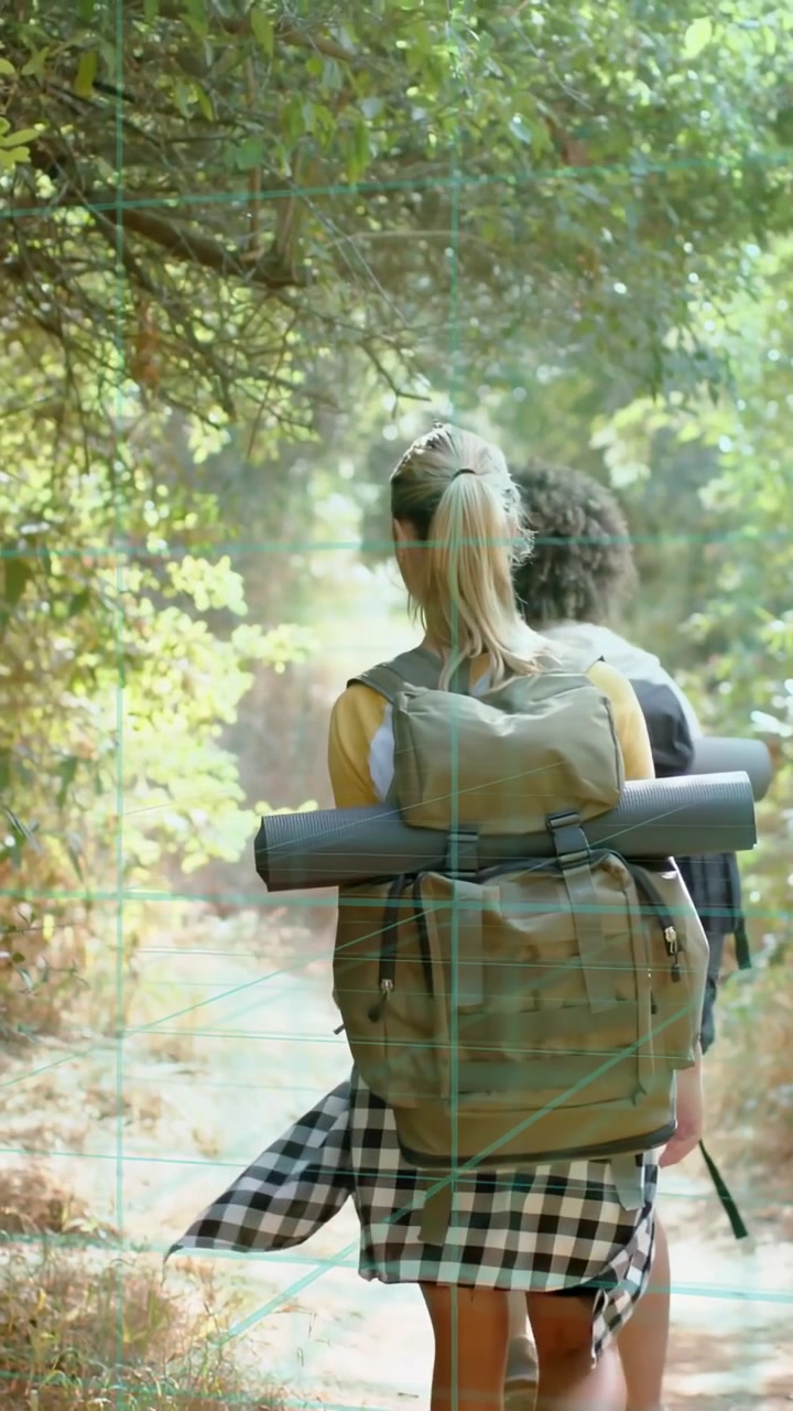 Vertical video: Two women hiking path for travel, adjusting pack and walking toward bright light