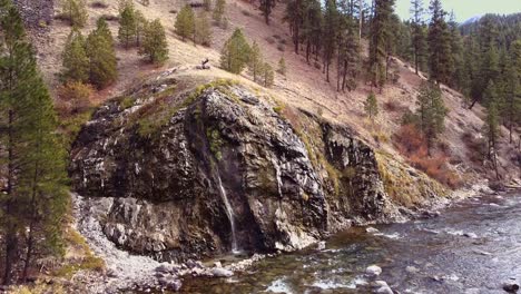 aerial drone shot approaching a hot spring waterfall in boise national forest in idaho located on boise river with steam rising and flowing water below