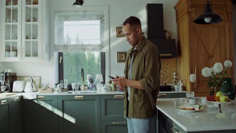 hombre usando teléfono inteligente en la cocina